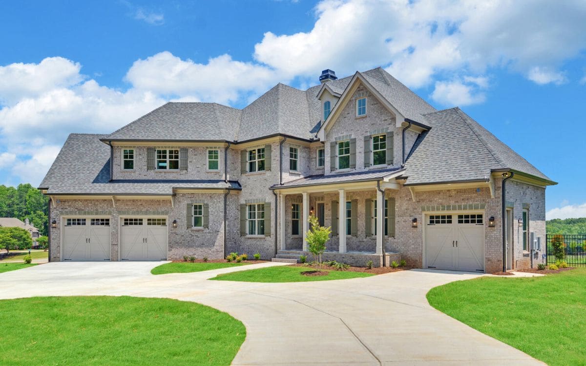 A large house with two cars parked in front of it.