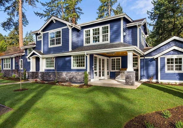 A blue house with white trim and green grass.